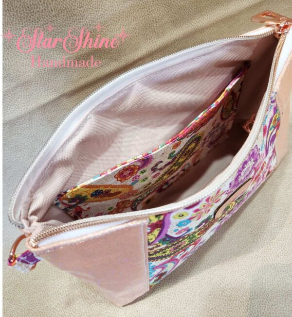 Stunning "Just Peachy" Sunshine Crossbody Crossbody. Measures 10 1/2" wise x 8" tall and 3" deep. $85.00 Colorful paisley floral fabric center, with striking holographic peach glitter vinyl. Rose gold hardware really ins striking in this combination. The exterior back also has a sipper pocket with rose gold zipper teeth and zipper pull. Matching adjustable strap in paisley and can be worn as a side strap or crossbody. Interior is waterproof canvas in rose gold color. It as a roomy slip pocket and zipper pocket.
